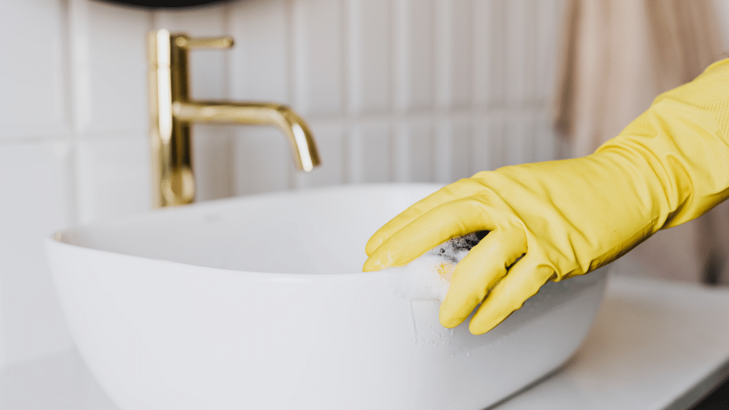 Gloved hand scrubbing a sink
